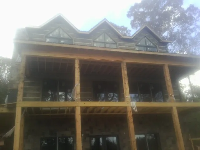 Dormers and porch framing on a large log home under construction — Roof Coating work by our crew in Jellico