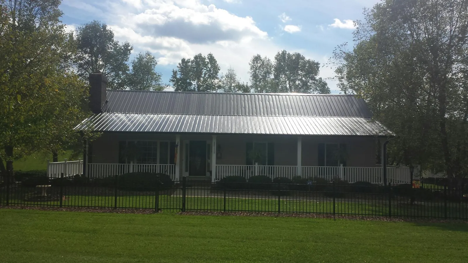 Gray metal roof on a brick ranch with a full width front porch — Gutter Guard Installation work by our crew in Jellico