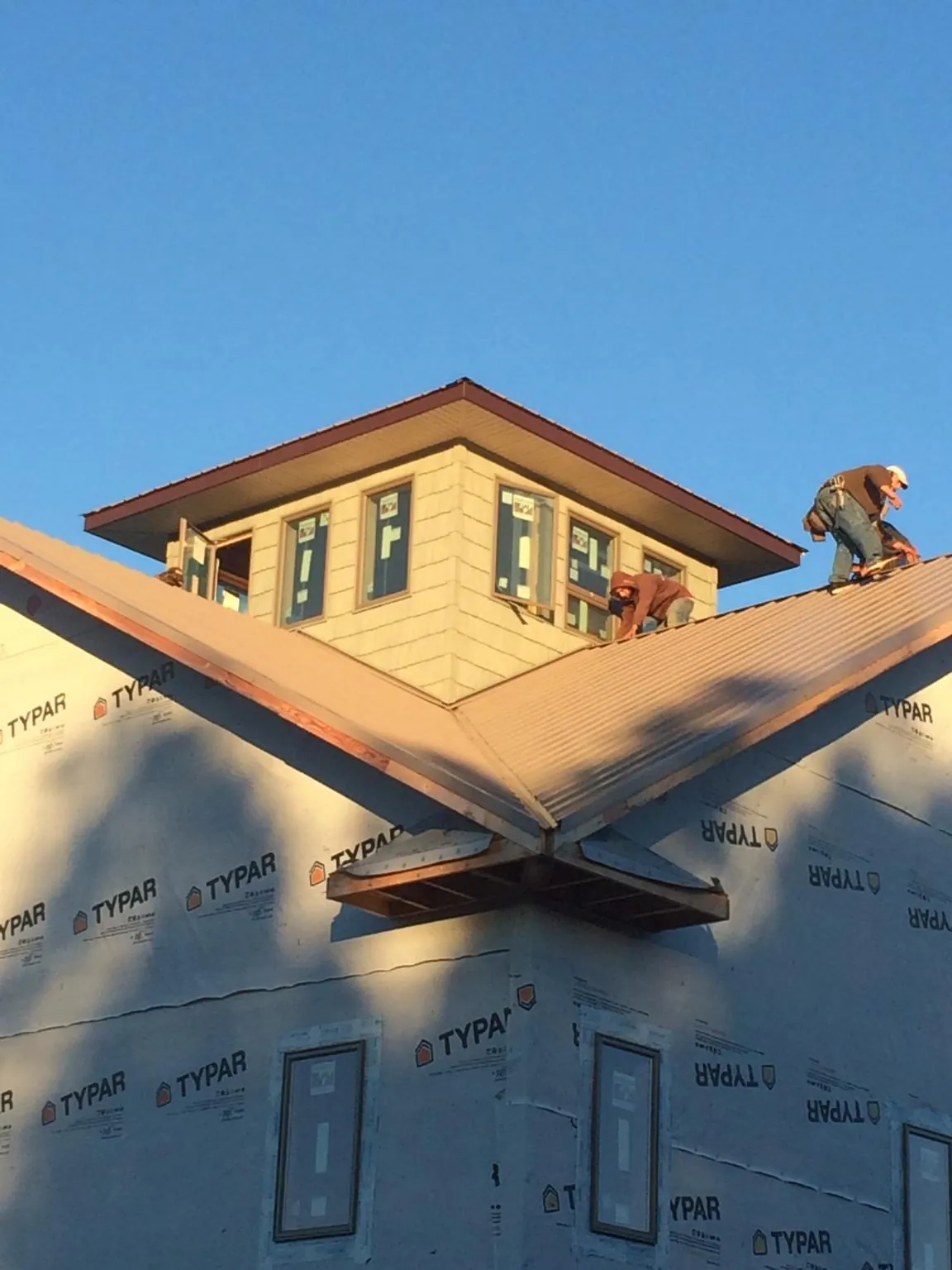 Roofers working around a rooftop cupola on a new metal roof at sunset — Roof Waterproofing in Jellico by Roofing Brothers
